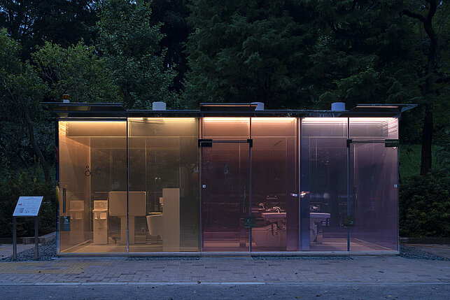 On display is the toilet house designed by Shigeru Ban. The three compartments are in the colors orange, red and purple. One can see inside. 