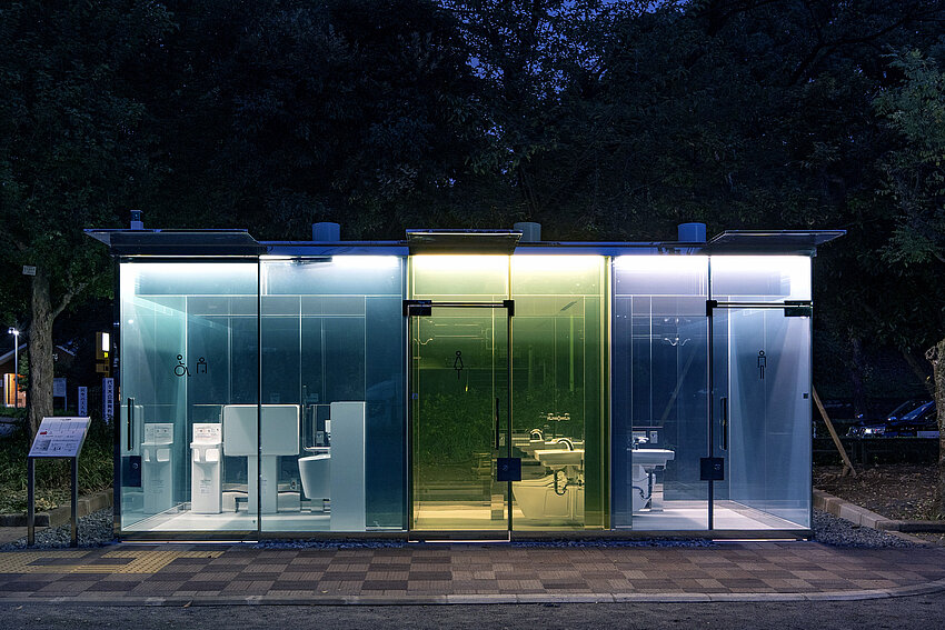 Three compartments of a toilet next to each other. They are blue, yellow and purple. You can see through the outer walls to the inside of the toilet.